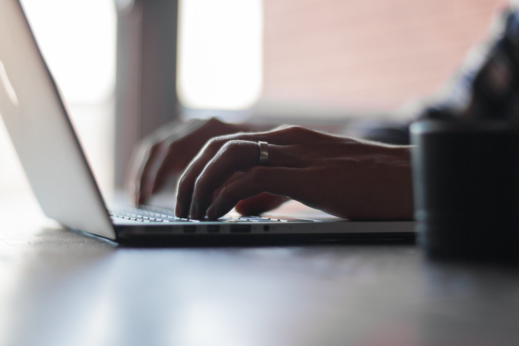 Close-up of hands typing on a laptop keyboard to draft a proposal