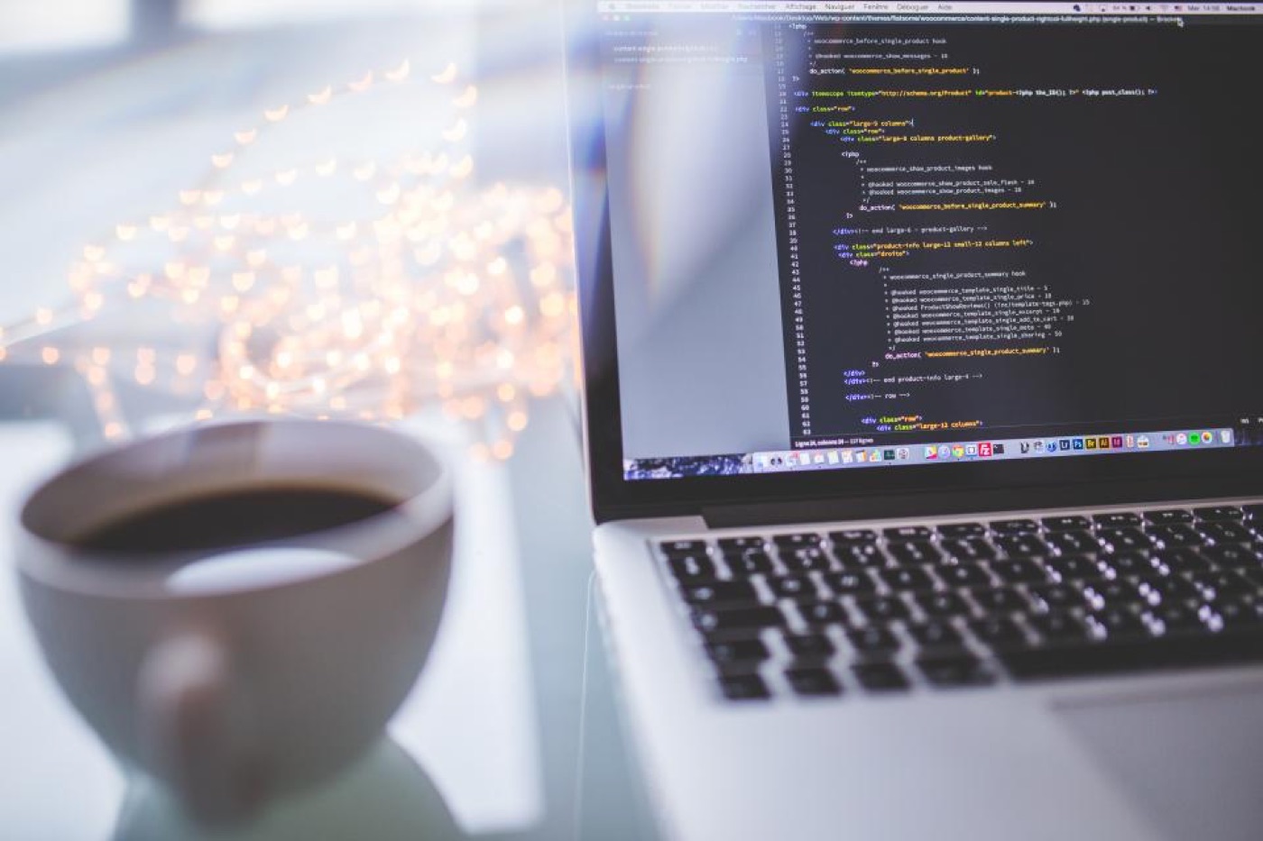 A laptop screen with code next to a cup of coffee