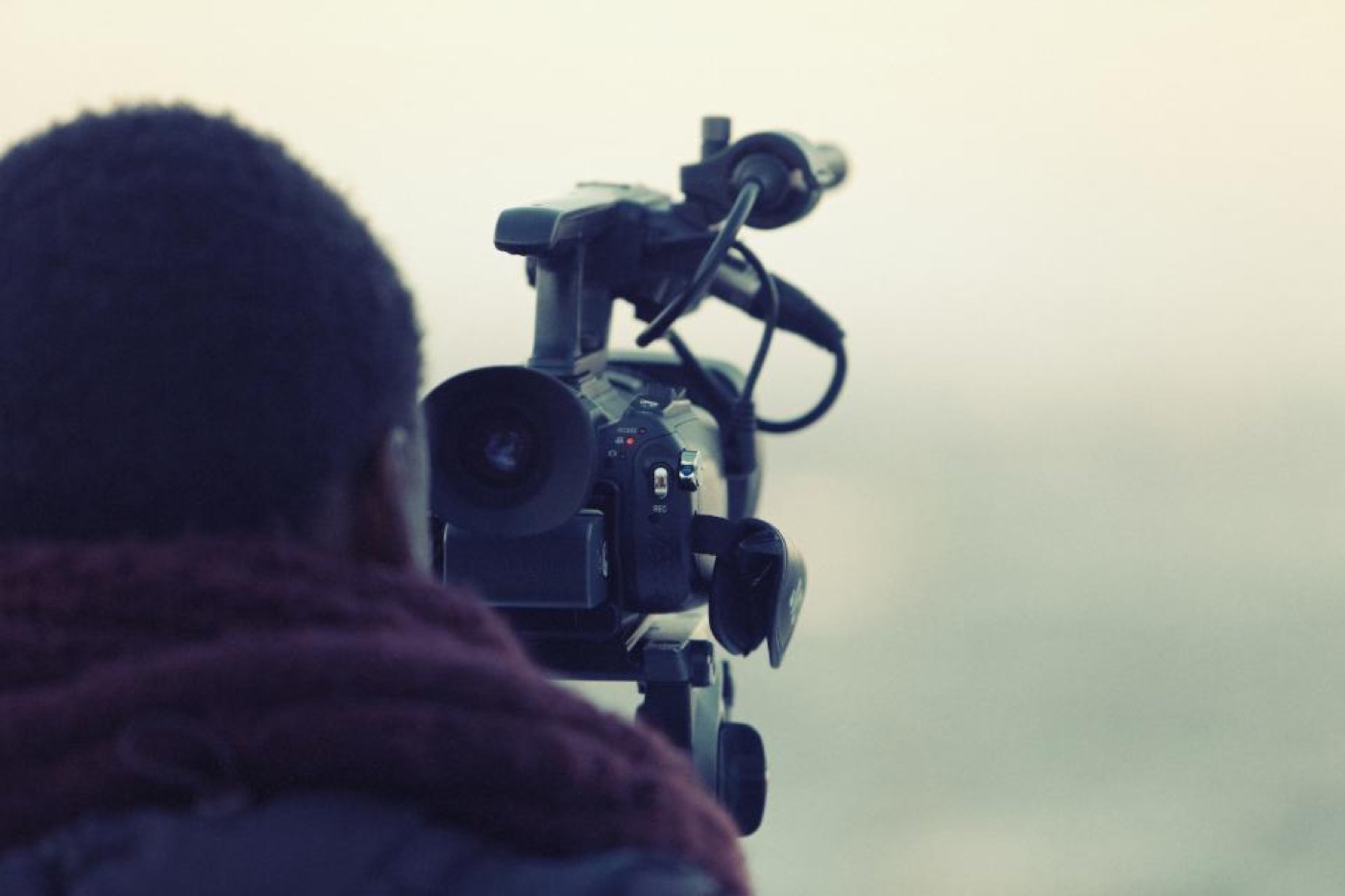A videographer filming with a shoulder-mounted camera